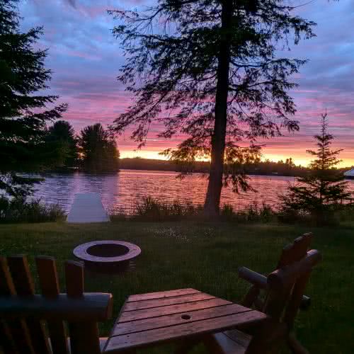 Smile Awhile 的戶外燒烤和用餐區，是夏季燒烤和家庭用餐的理想場所，周圍環繞著自然風光和高大的松樹。